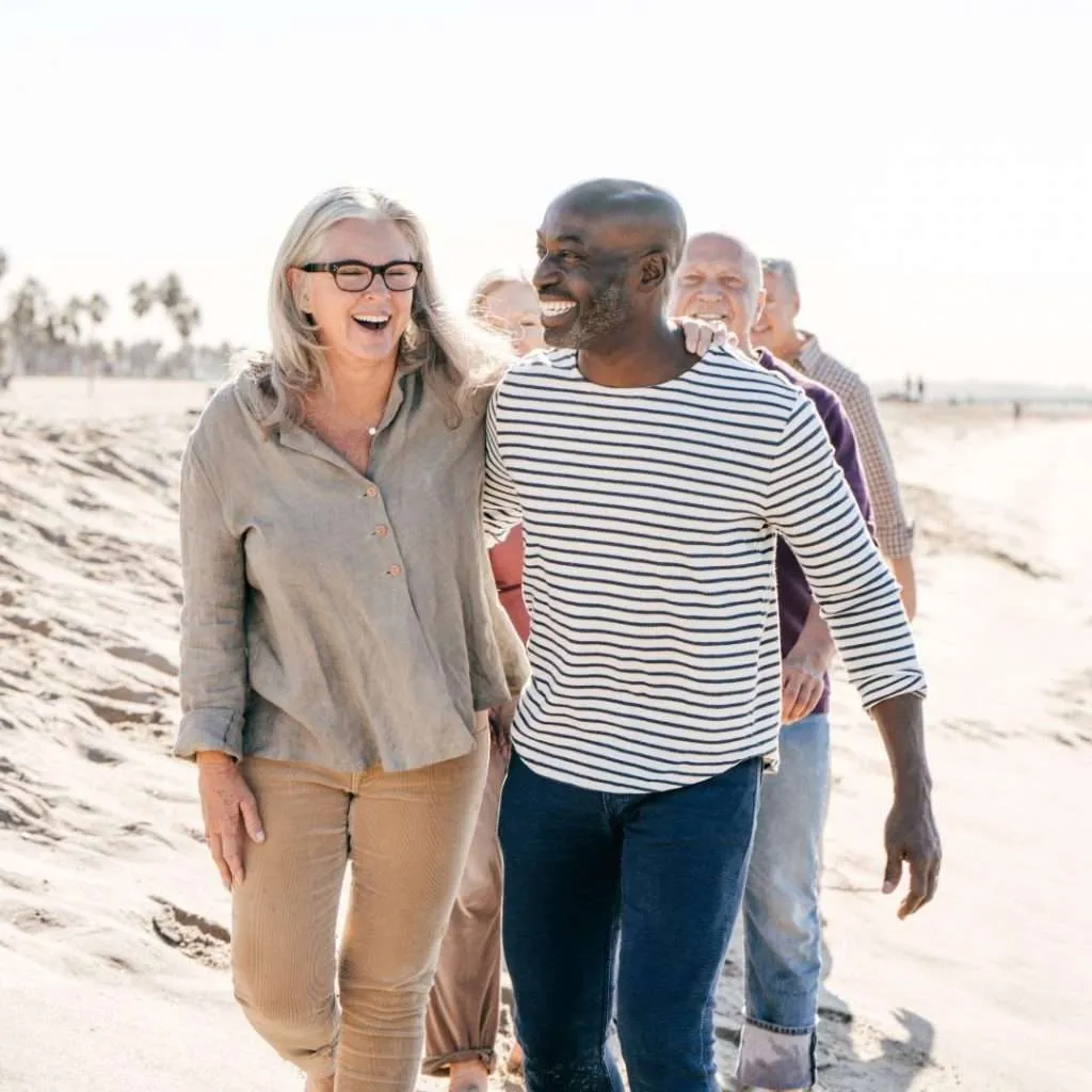 Older couples enjoying a walk on the beach in retirement.