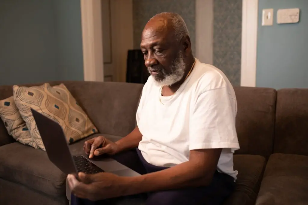 elderly man sits using a laptop