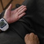 A senior adult using a wrist blood pressure monitor at home, focusing on health management.
