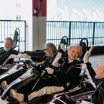 Senior adults having fun racing go-karts indoors, showcasing joy and friendship.