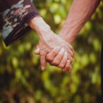 A touching image of elderly couple holding hands, symbolizing love and companionship in a natural setting.