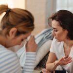 Two women indoors having a conversation, displaying signs of disagreement and stress.