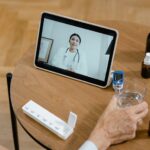 Senior adult having a virtual doctor consultation on a tablet with medications on the table.