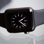Close-up of an elegant black smartwatch with a minimalist classic dial on a light background.